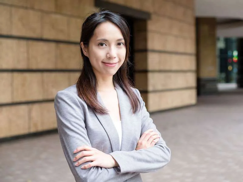 woman wearing a professional jacket and smiling with a building in the background
