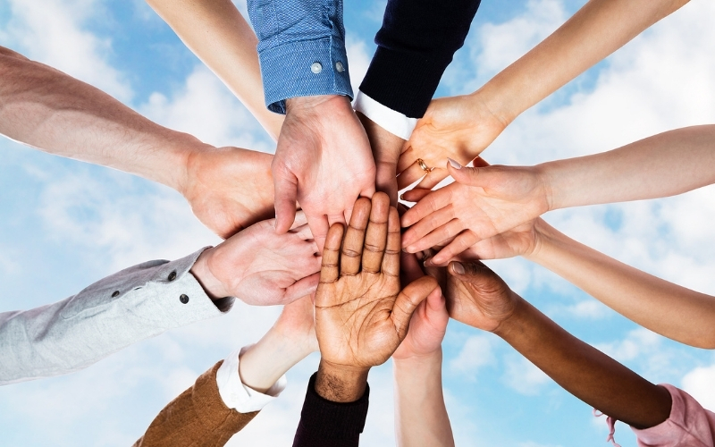 Diverse group of people joining hands for teamwork