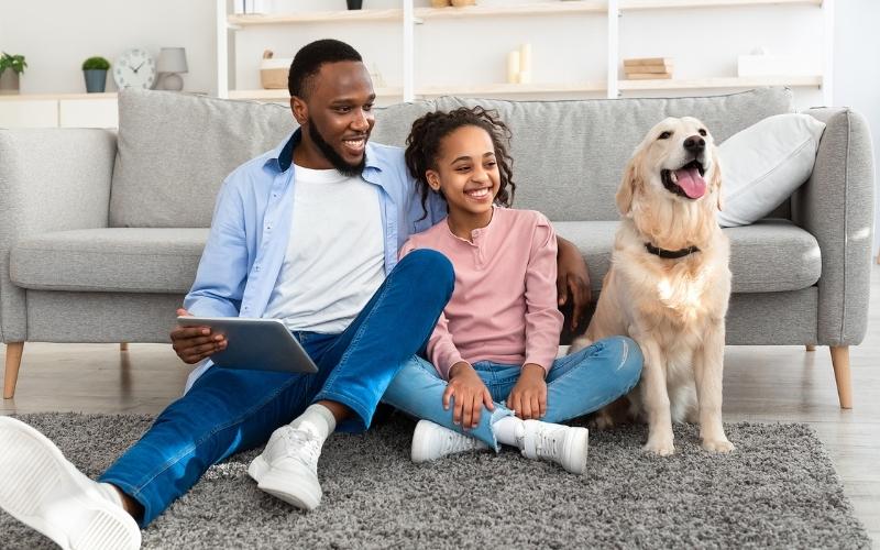 two kids smiling with a dog by the couch