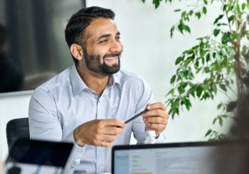 Business man behind computer smiling and holding a pen