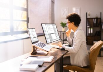 Woman working from home on multiple screens