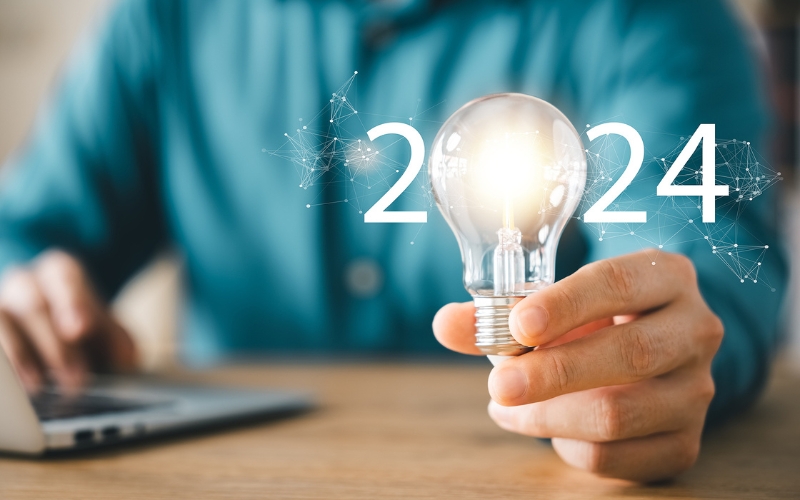 Man in blue shirt holding lightbulb that acts as the zero in the date 2024