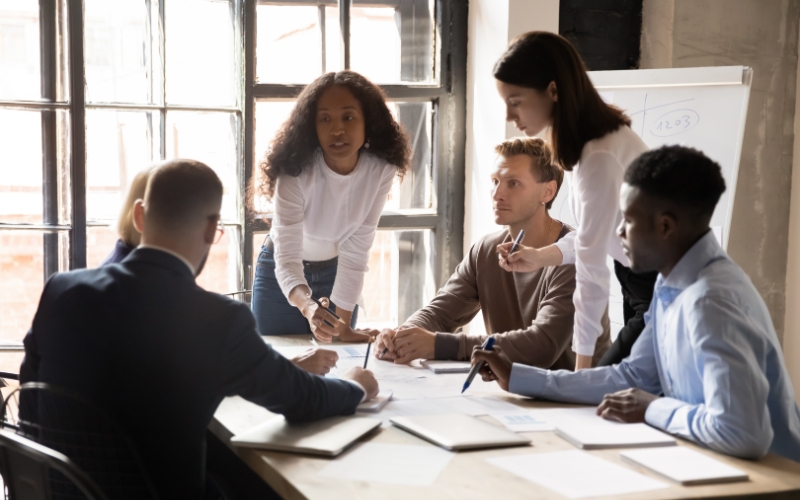 six professionals collaborating in person in an office with large windows